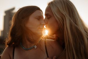 Two people share an intimate moment as the sun sets behind city buildings.