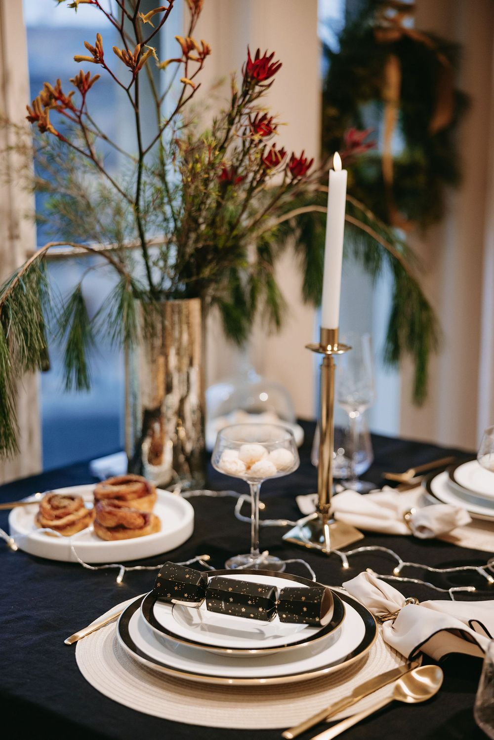Elegant table setting with white plates, black tablecloth, candles and floral centerpiece for an upscale dinner event.