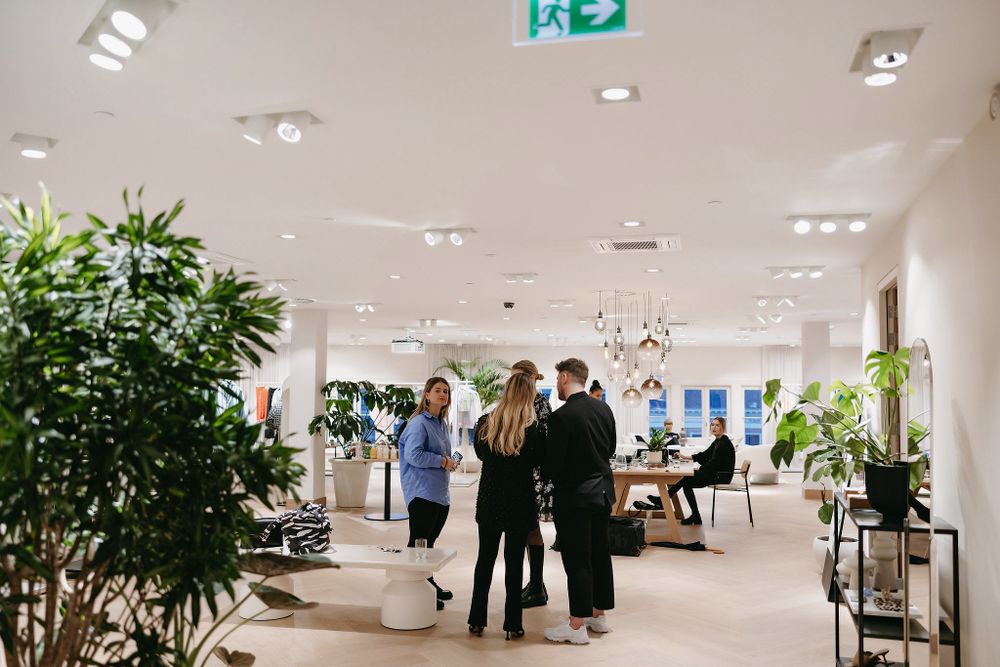 Bright retail space with indoor plants and people gathering for a business event.