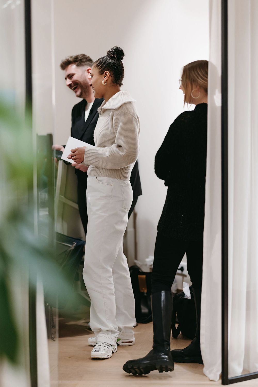 Casual conversation in a bright retail space with white and black outfits.