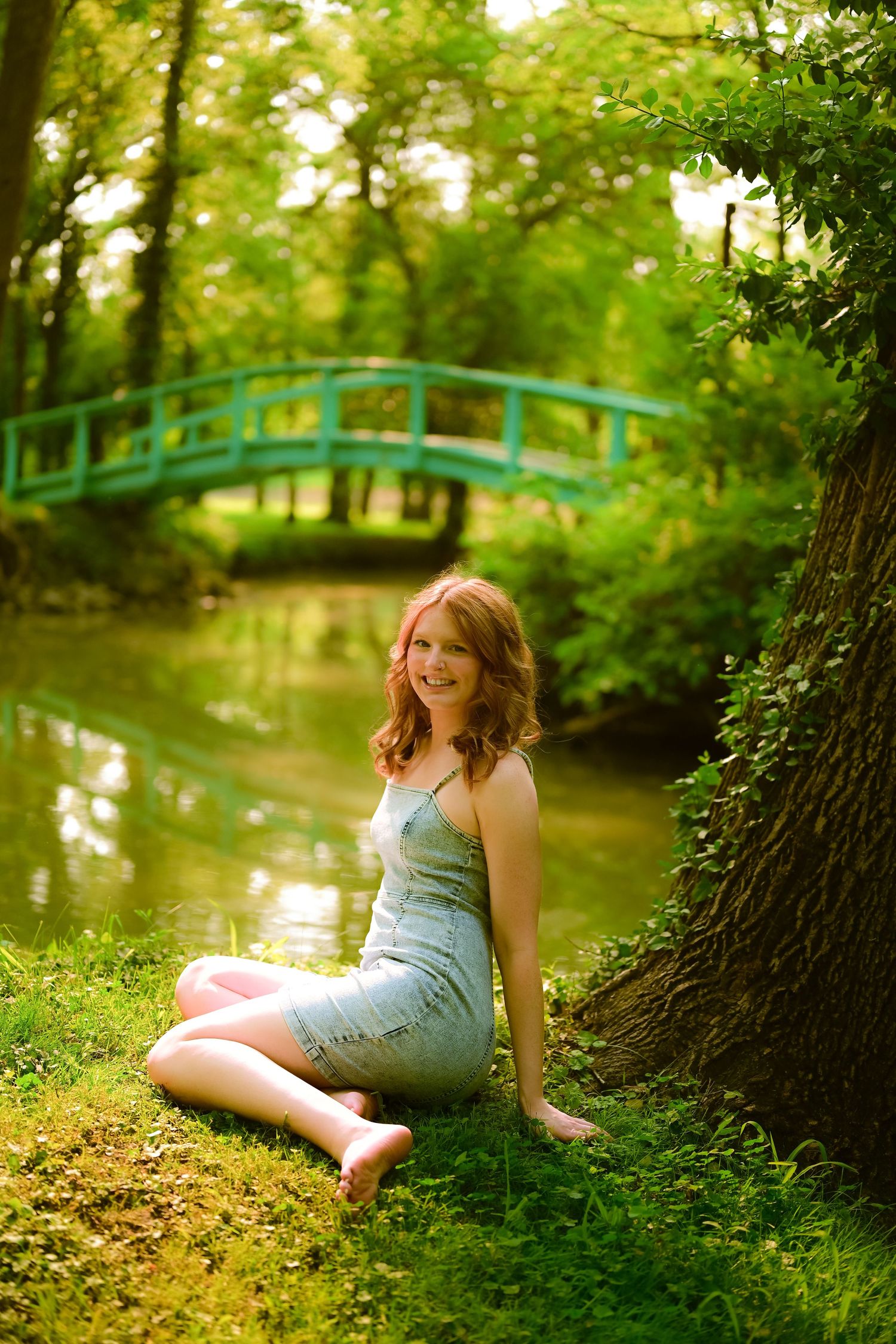 A couple embraces under lush green trees in a sunlit park or garden setting.