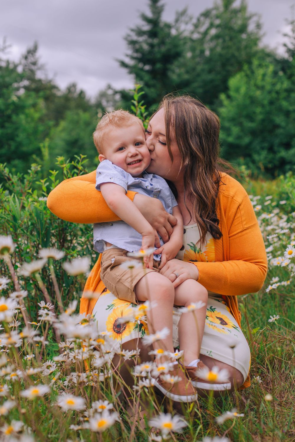 A tender moment between parent and child among blooming daisies in a summer field. Spokane Liberty Lake Photographer Family Photographer
