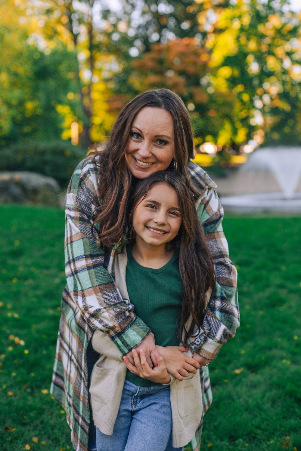 A warm embrace shared between two people in a park with autumn trees in the background. Spokane Liberty Lake Photographer Family
