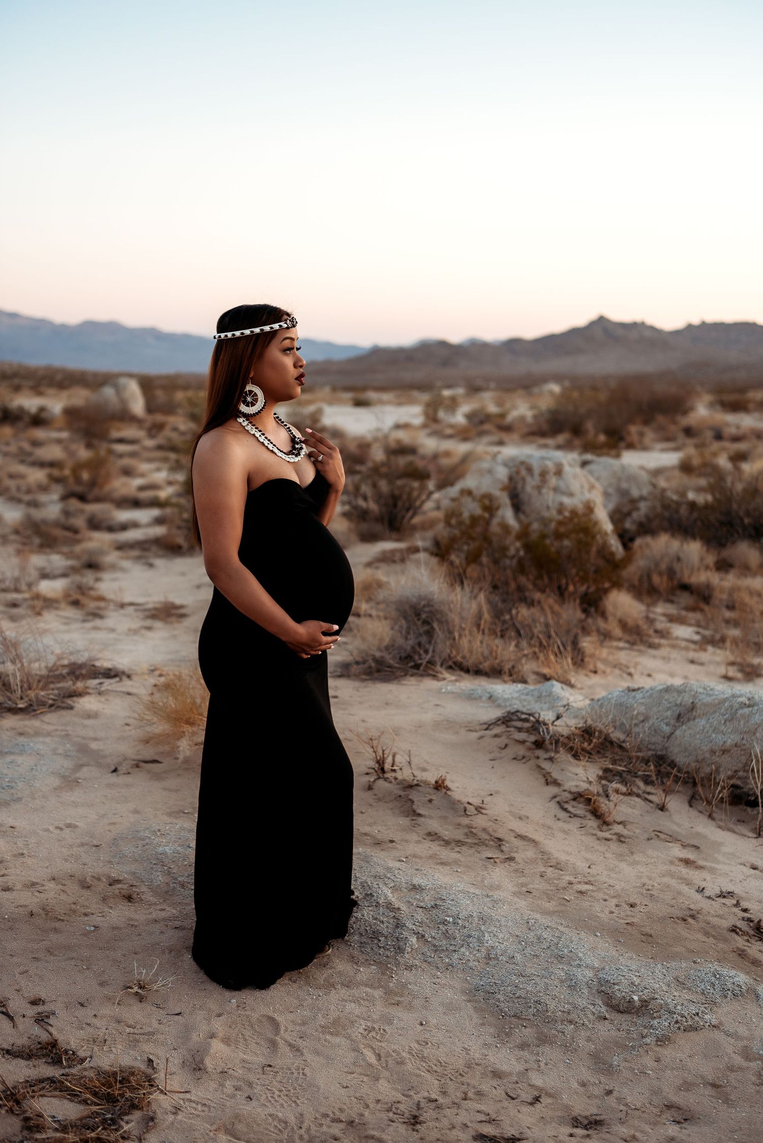 expecting mother dressed in black in middle of desert.