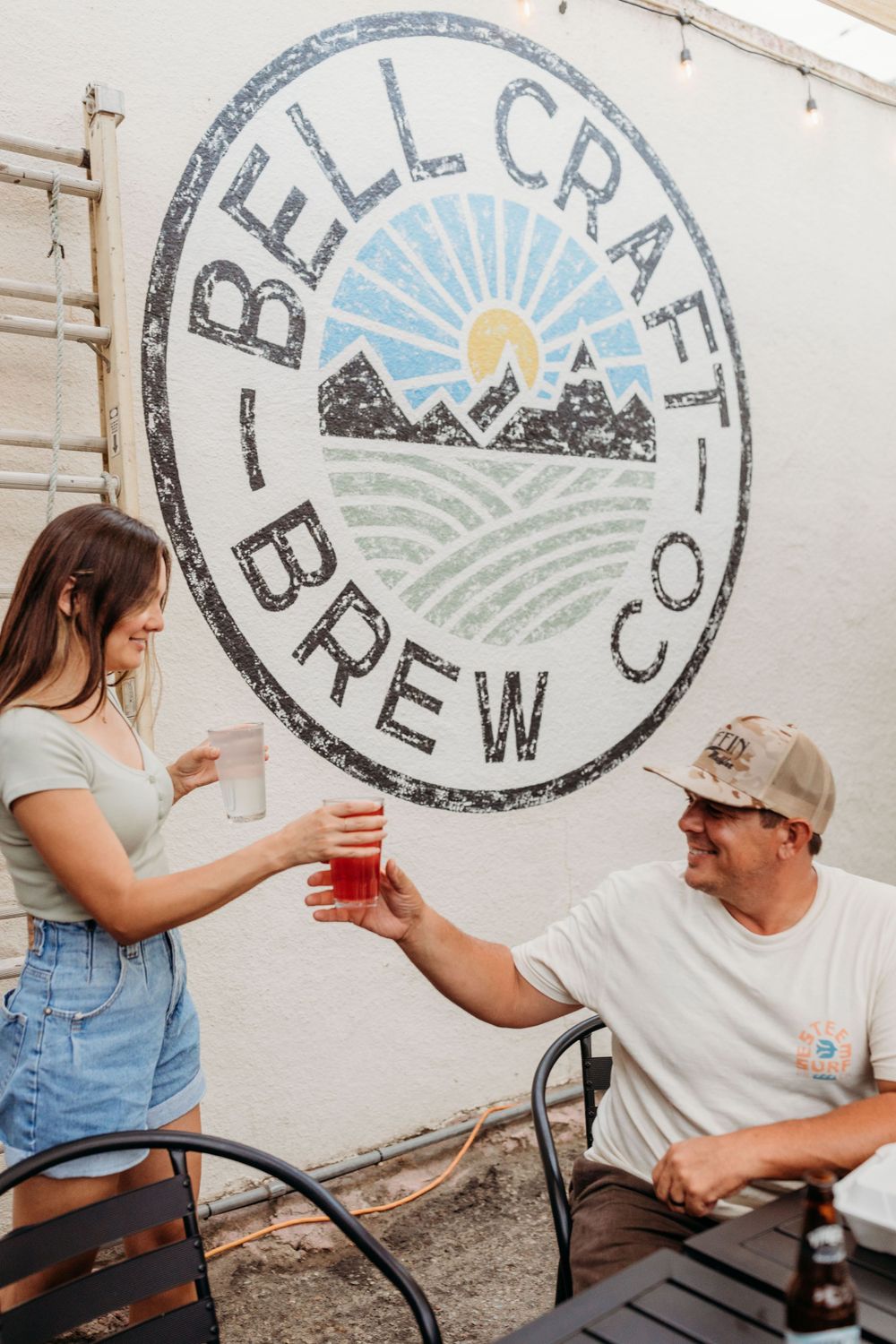 Bell Craft Brew Co logo painted on white wall featuring mountain and sunrise design.