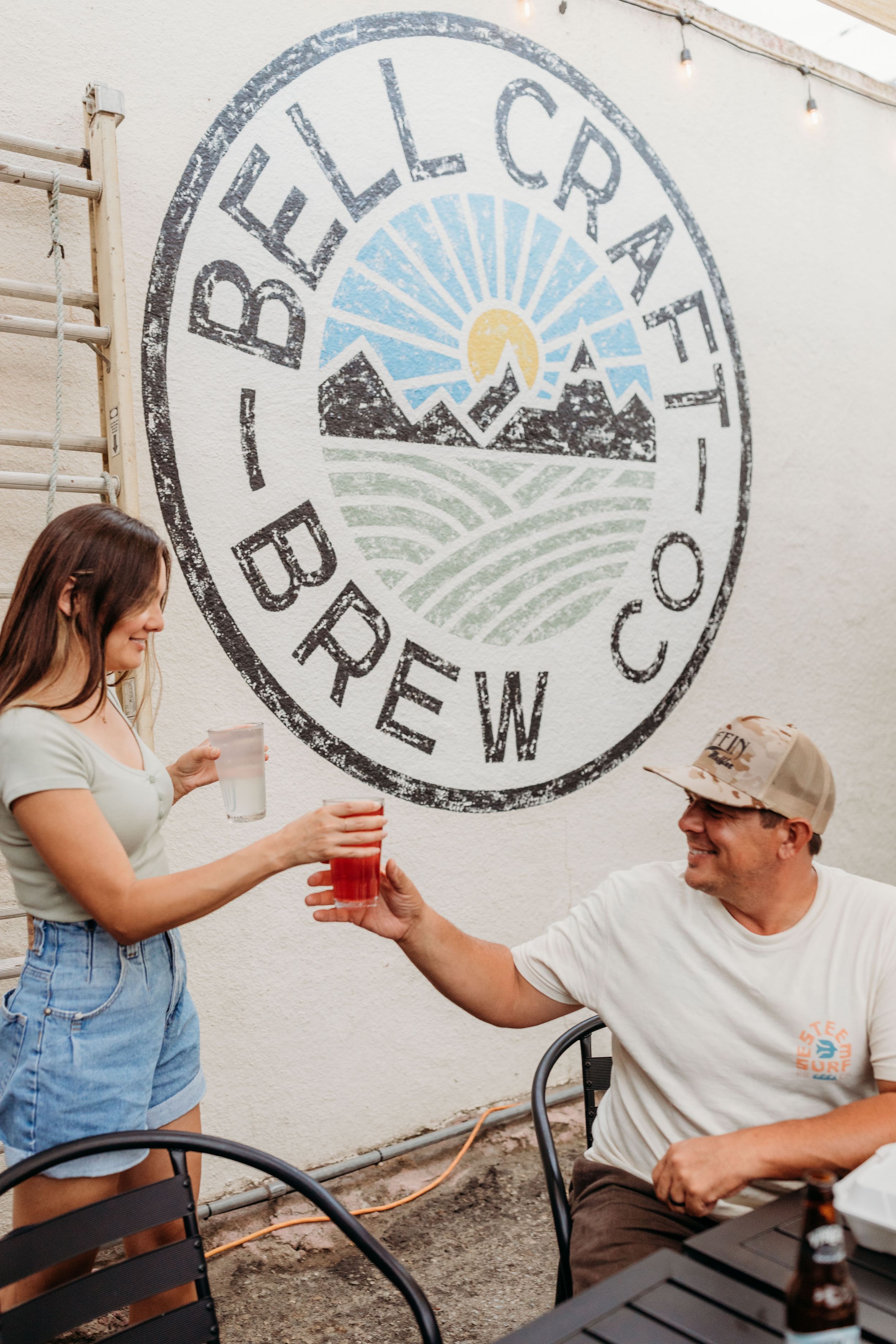 Bell Craft Brew Co logo painted on white wall featuring mountain and sunrise design.