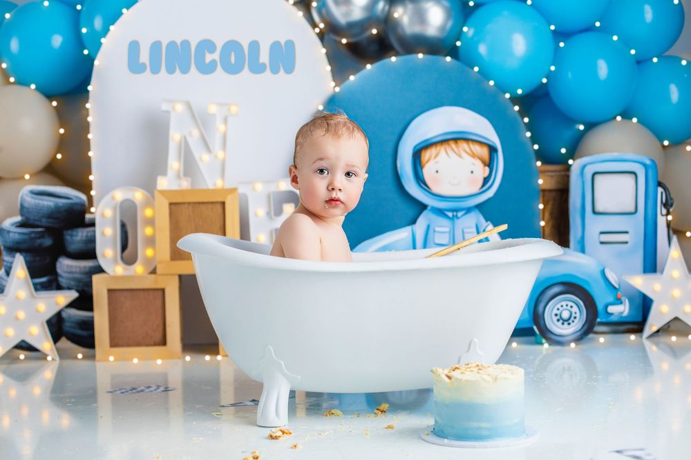 Blue and silver winter themed first birthday party decorations with a cake, balloons, and gifts on display.Best cake smash photographer Ipsw