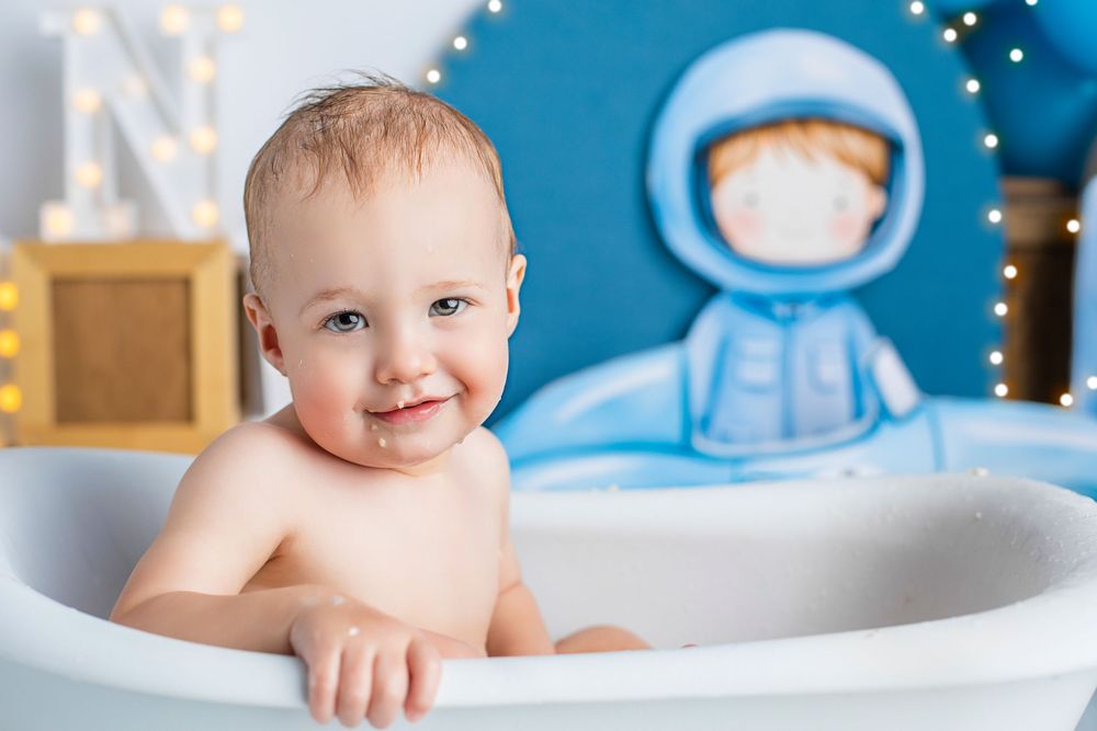 A baby and bath toys play during bath time in a white bathtub.Luxury first birthday portraits Ipswich – cake smash photography by Salma Begg