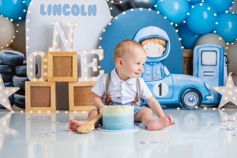 Baby boy's first birthday cake smash photoshoot with vintage car theme and blue decorations,.Professional cake smash