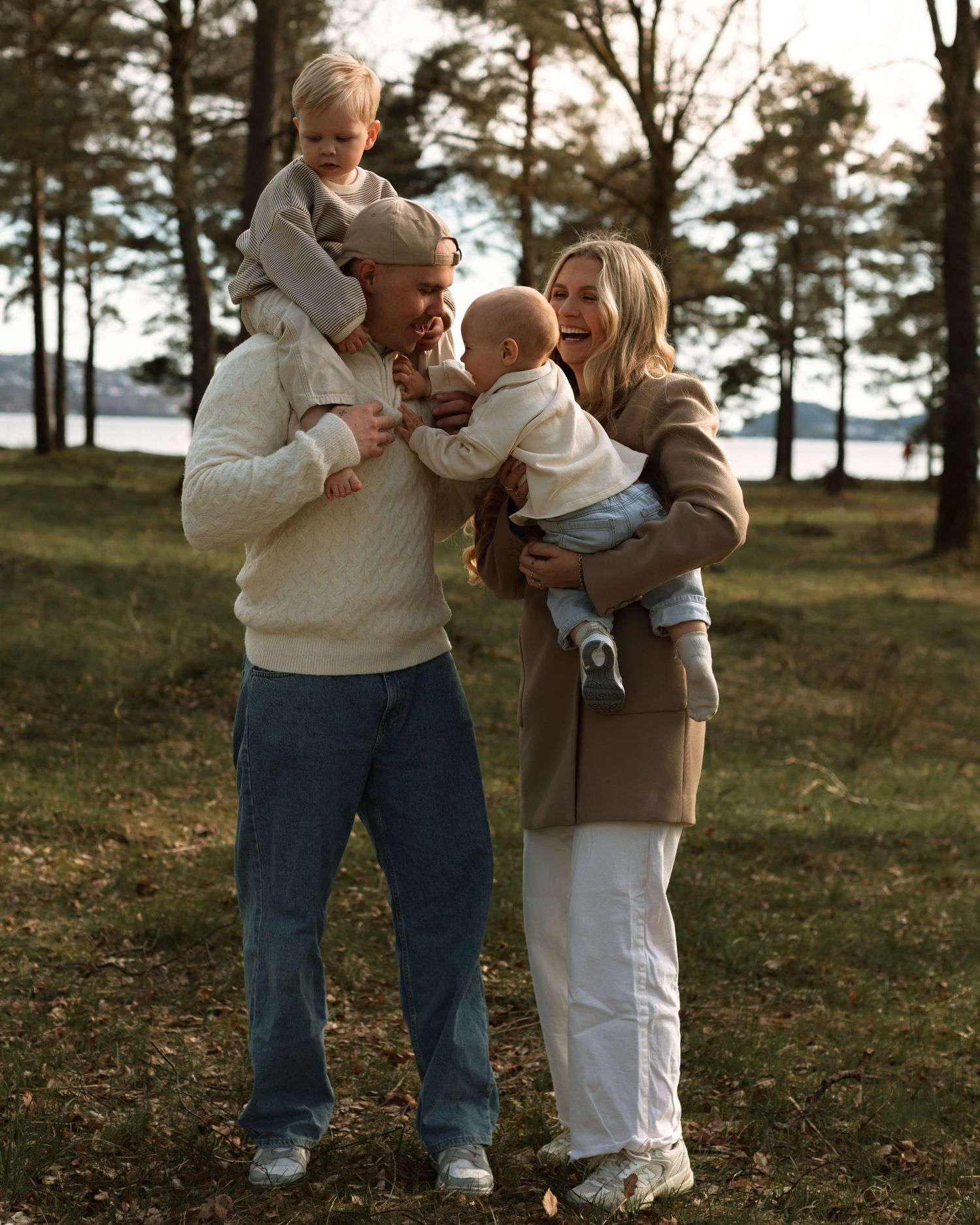 Familie som smiler og ler sammen i skogen ved vannet