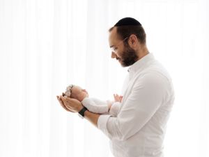 A tender moment captured in white as a parent holds and gazes lovingly at their newborn baby.