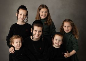 Studio portrait of siblings in dark clothing against grey background.