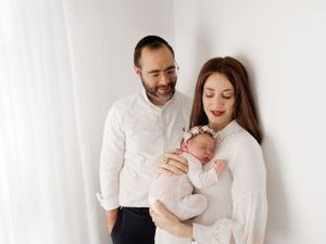 Family moment in white attire against minimalist background.