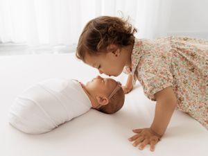 Young siblings sharing tender moment on white background.