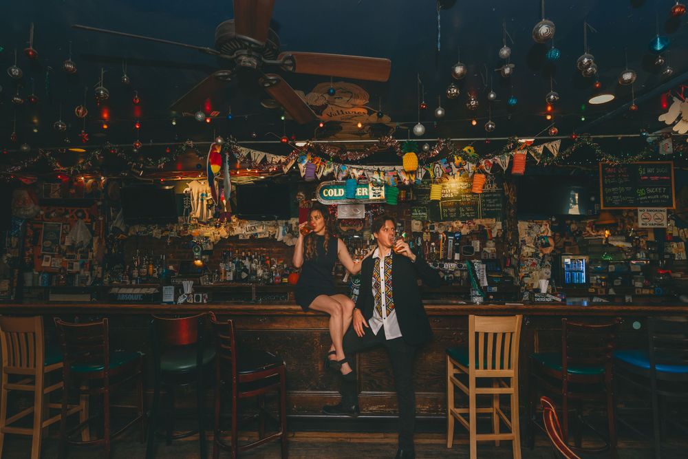 A dimly lit rustic bar interior decorated with colorful lights and vintage decor creates a cozy nighttime atmosphere.