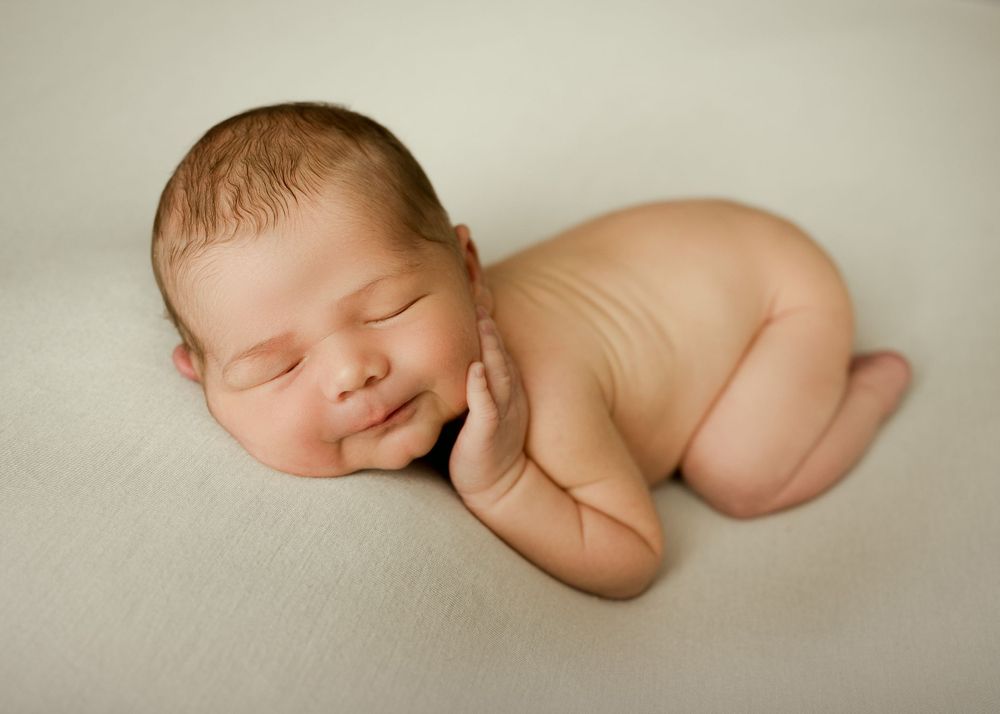 Soft artistic newborn photography in Fort Saskatchewan studio against minimalist beige backdrop.