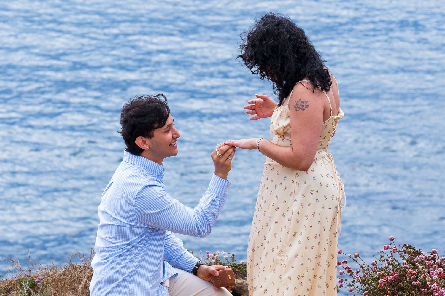 A photo of a man getting down on one knee to propose to his girlfriend to make her his fiancee. Beach proposal photo shoot in Garrapata park