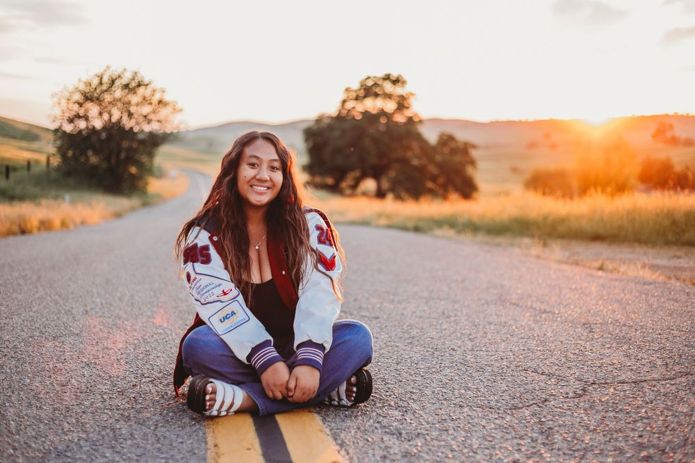 Portrait shoot of a teenager sitting on a country road at sunset
