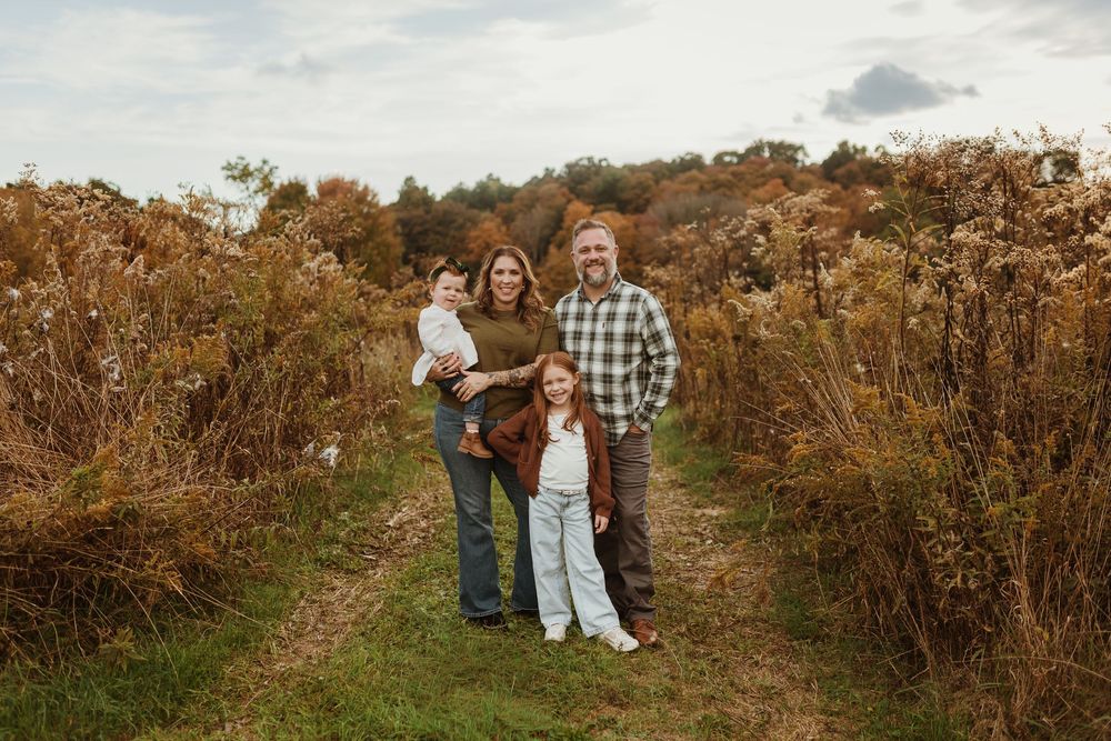 a young family smiling and posing in an autumn field