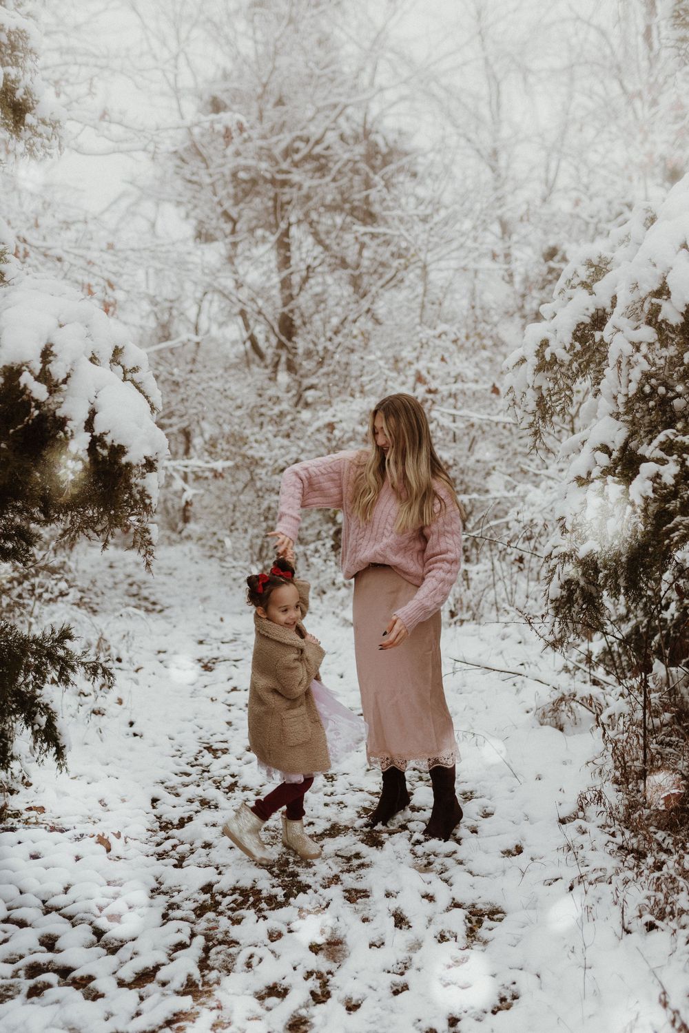 a mother spins her young daughter like a ballerina in a snowy scene