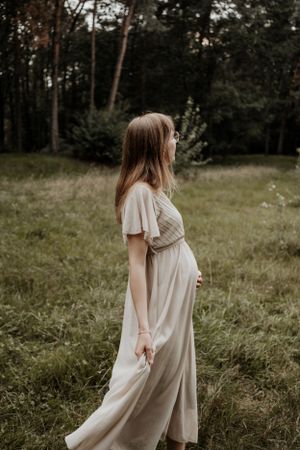 Zwangere vrouw laat haar buik zien in een mooie jurk