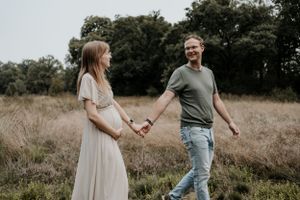Zwangere vrouw loopt met haar man door een grasveld
