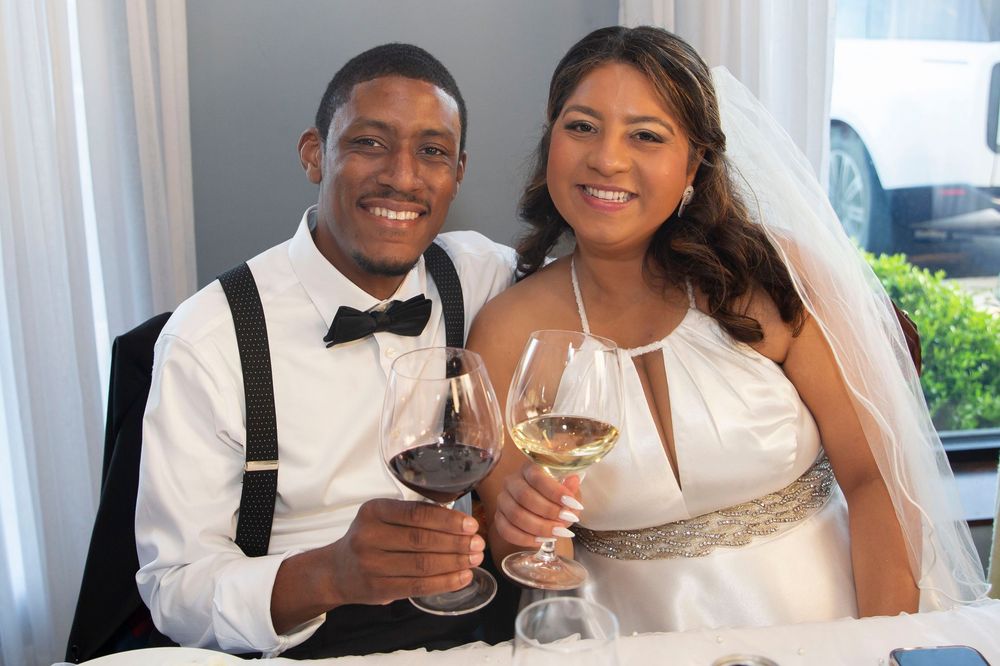 Smiling newlywed couple toasting with wine glasses at their wedding reception.