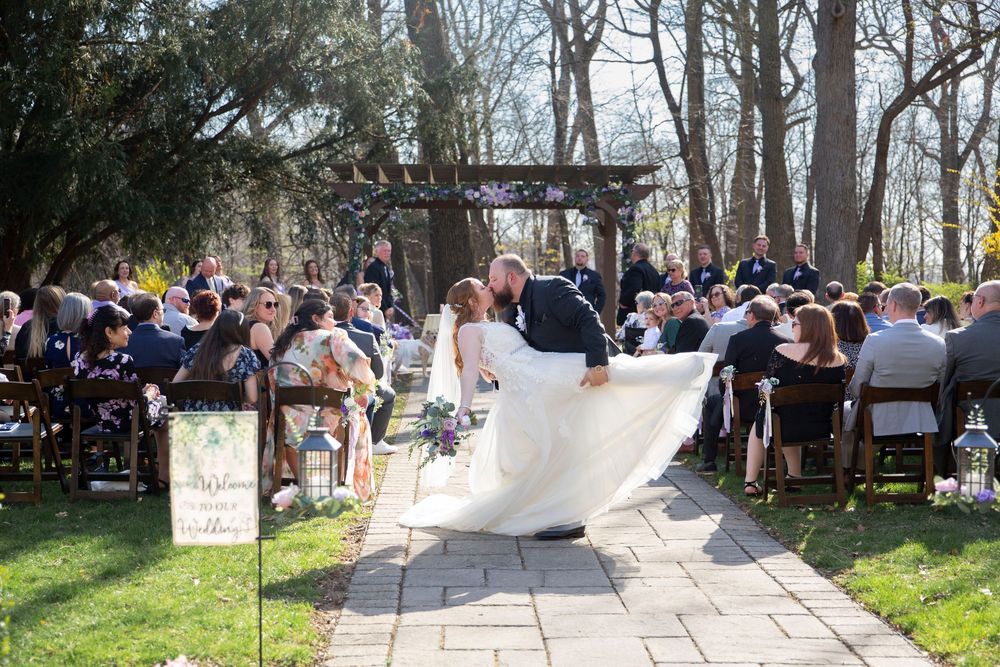 Bride and groom share a kiss while walking down the aisle at an outdoor wedding ceremony.