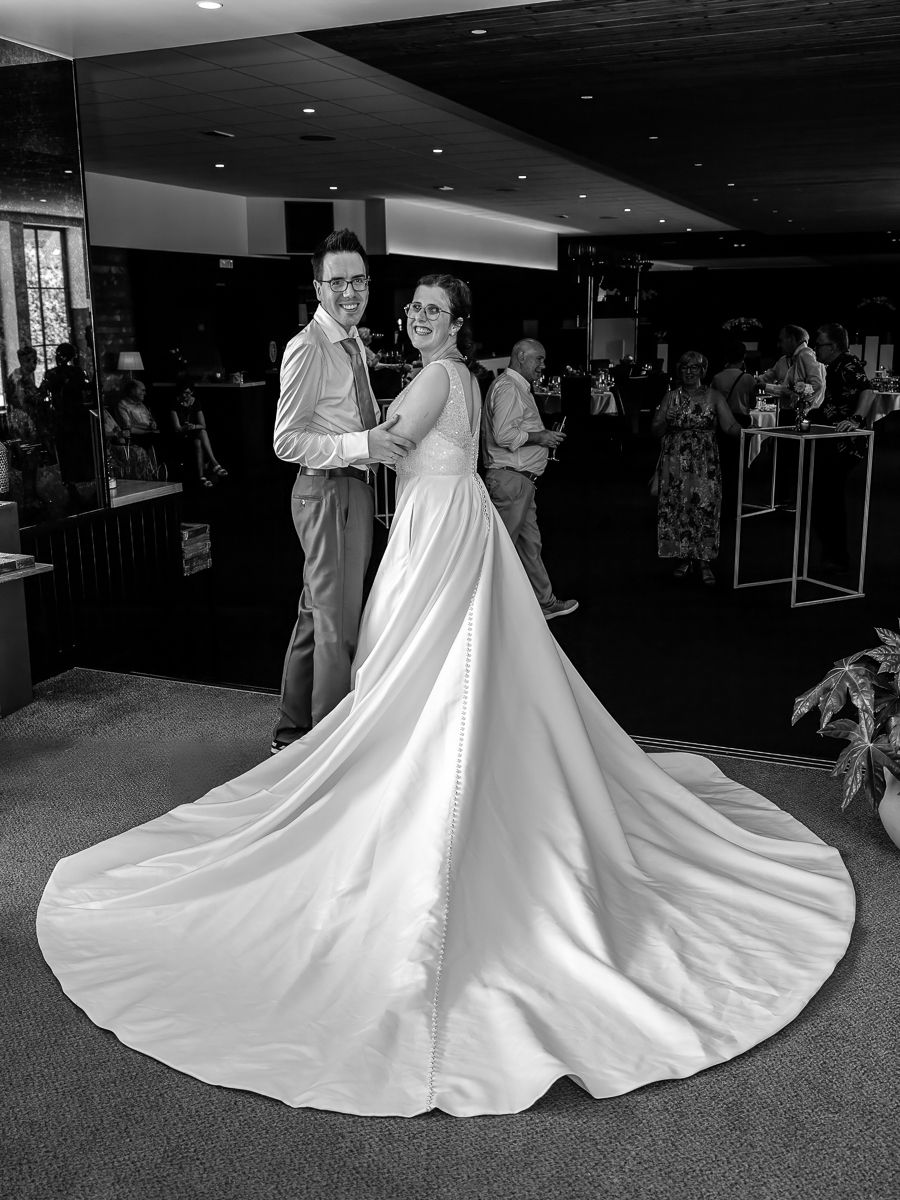 Black and white photo of a bride in a flowing gown and groom dancing at their wedding reception.