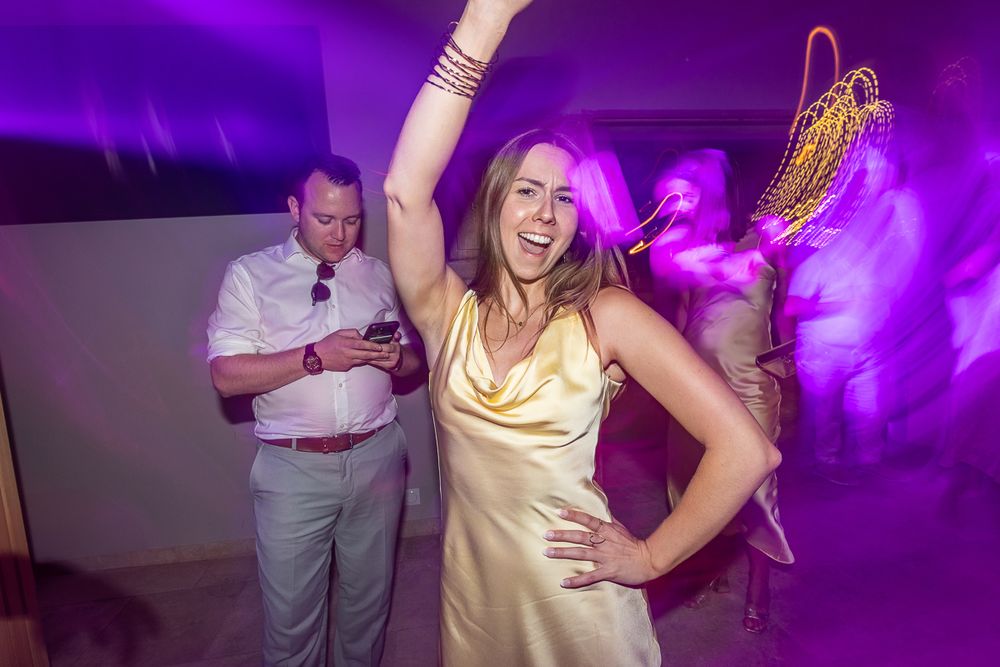 Wedding reception dance party with purple lighting and guests enjoying the celebration on a dance floor.