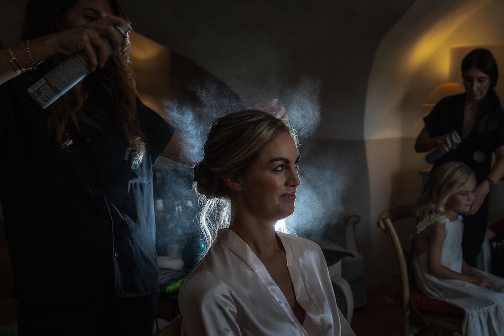 Someone getting their hair styled in moody lighting with hazy smoke or mist in the air during preparation.