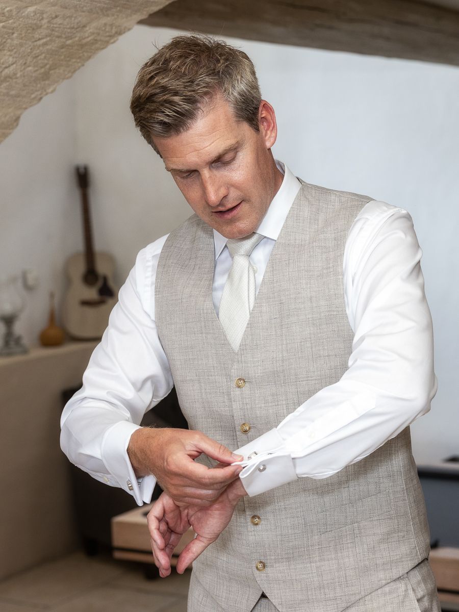 A person in a white dress shirt and light gray vest adjusts their sleeve cuffs in a series of motion shots.