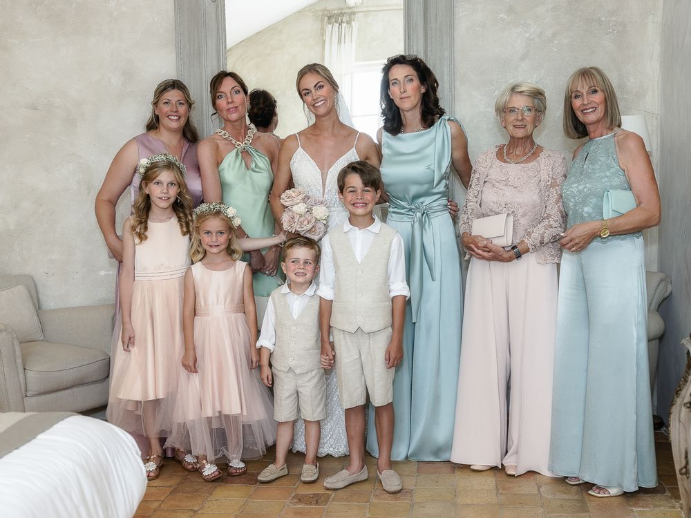 A formal group portrait showing a wedding party in coordinated pastel dresses of mint, blue and pink standing together.