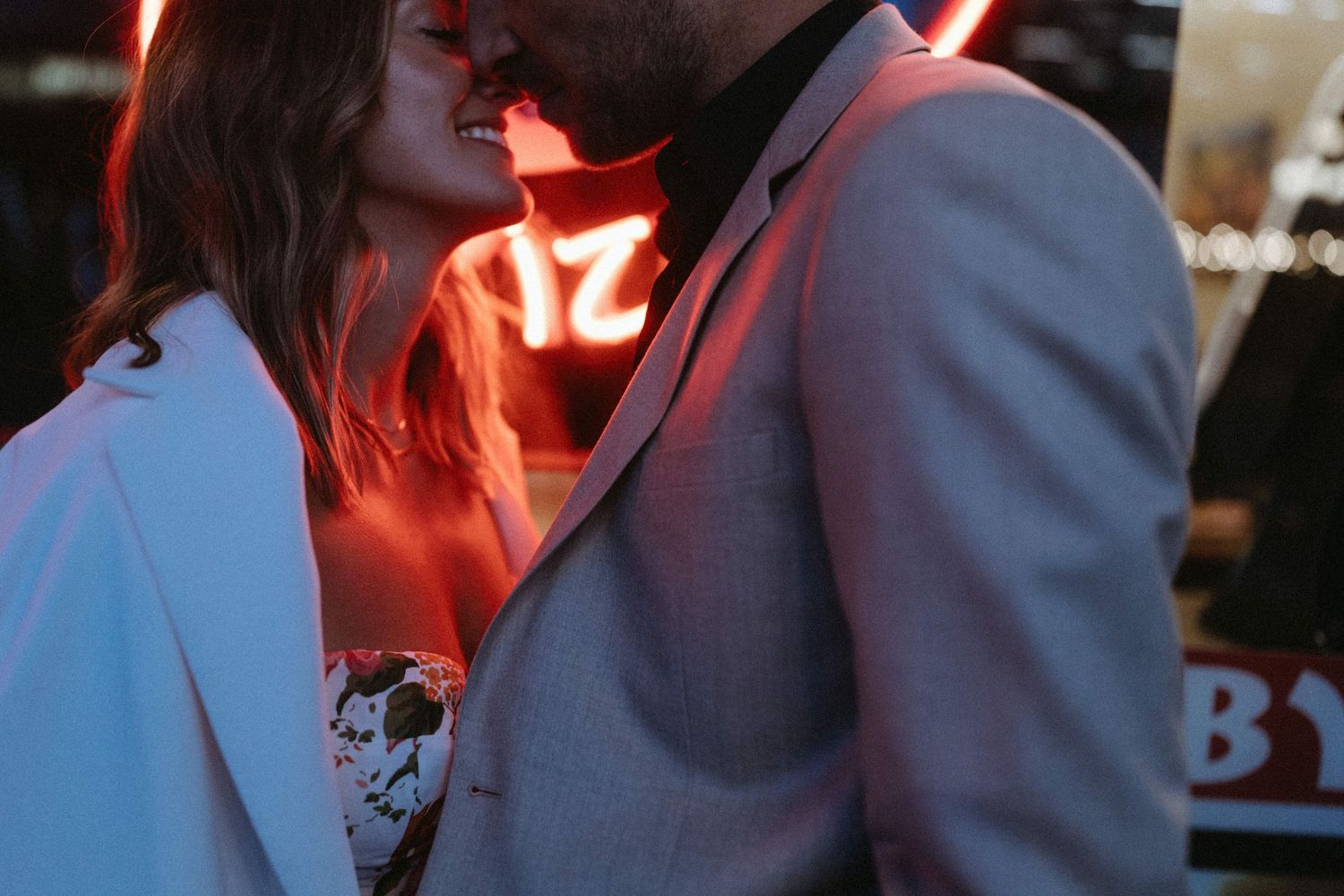 Couple in formal wedding attire dancing together at a reception in a dimly lit venue.