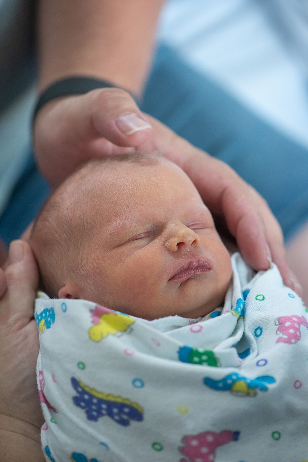 Photo of a newborn taken from above and in her parents hands. Taking in a hospital room - Kelly Chapman Photographer Perth