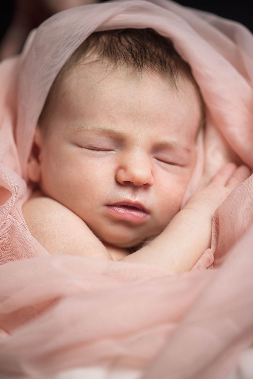 Close up photo of a newborn sleeping and wrapped with pink soft cloth - Kelly Chapman Photographer Perth