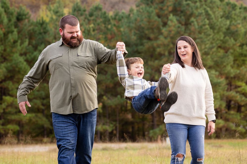 Parents swinging their child between them during a family session in Mountain Home, Arkansas