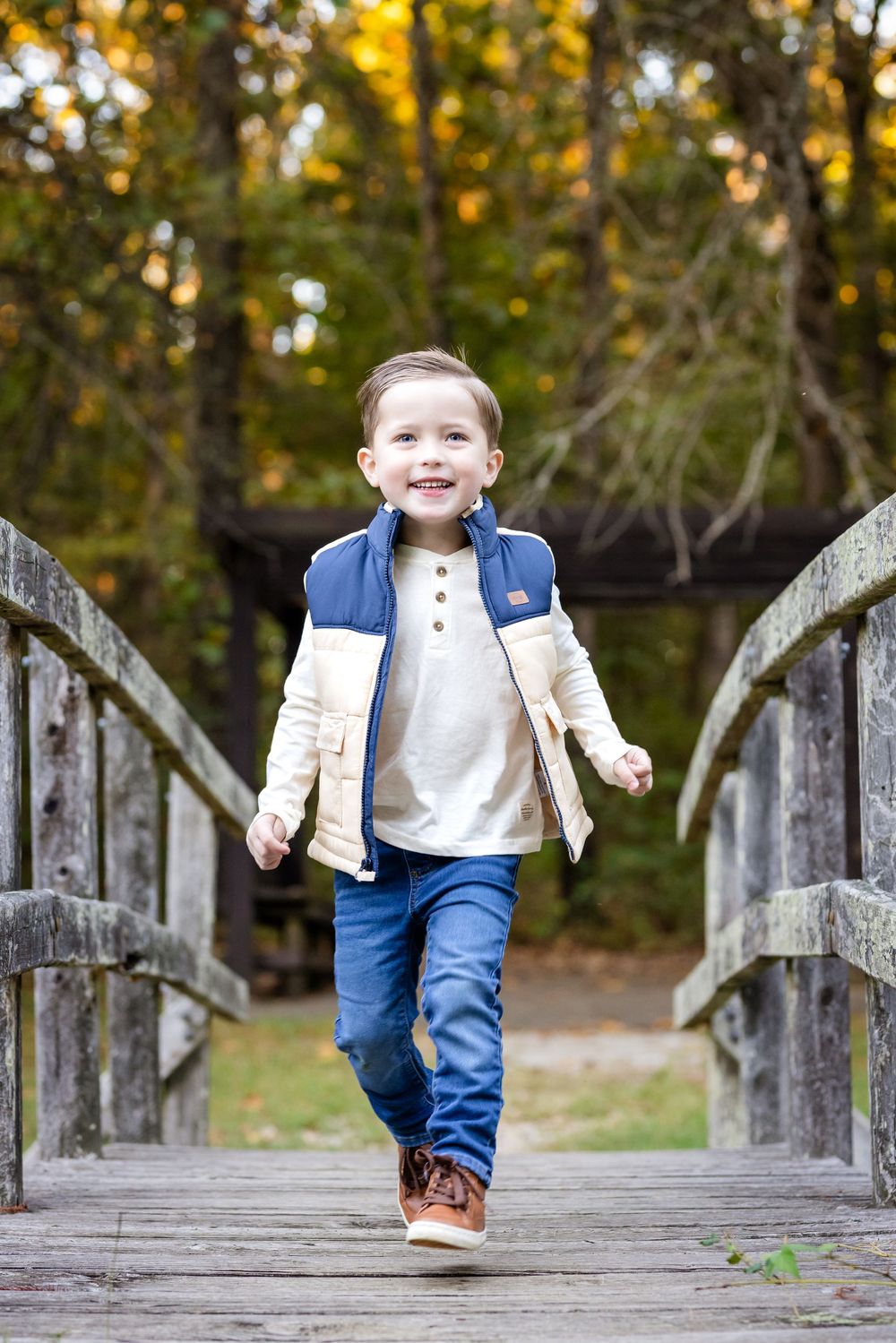 Young boy walking across a wooden bridge during a family session in the Twin Lakes area of Arkansas