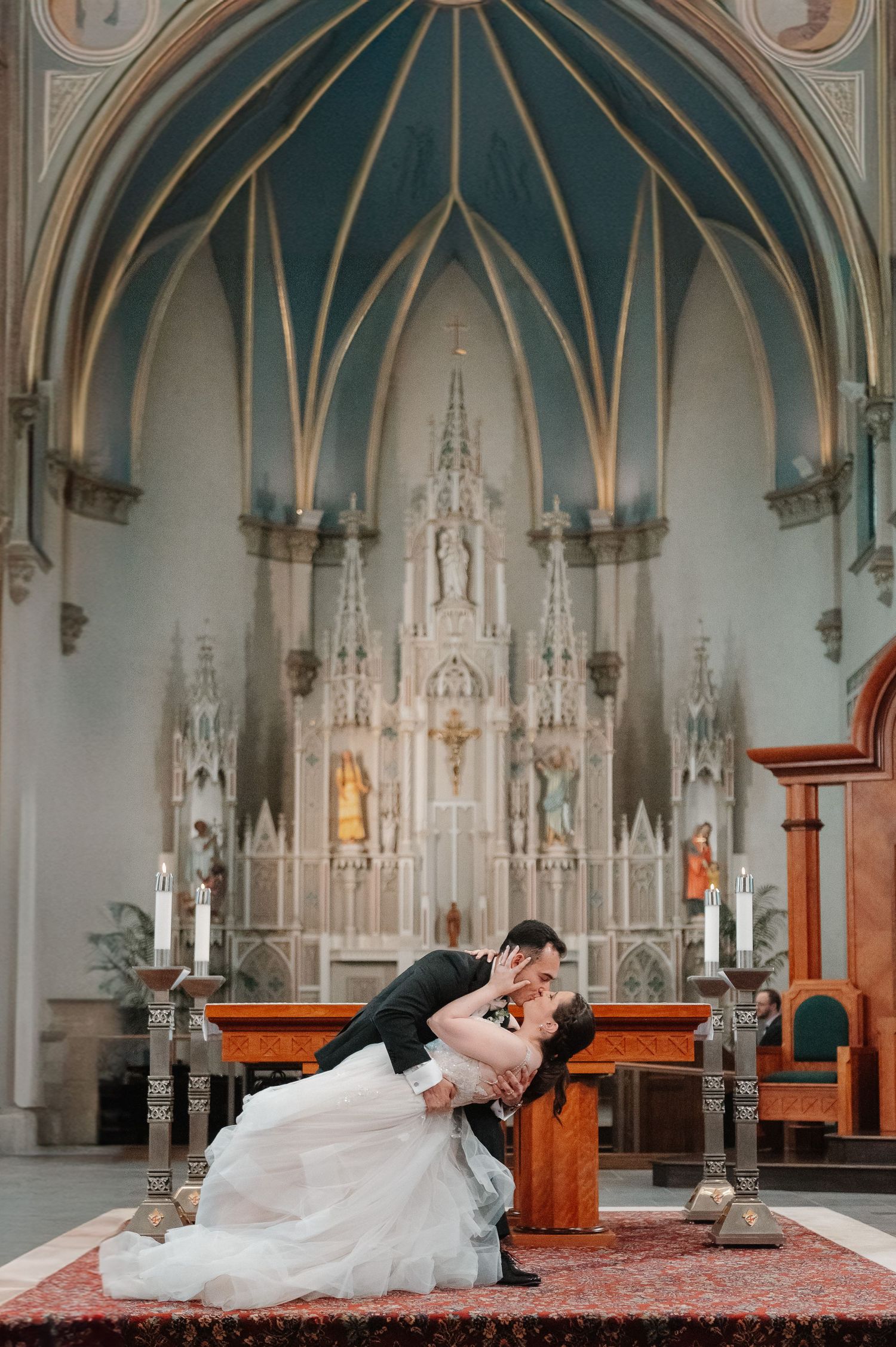 A romantic wedding dip pose in an ornate gothic church with a dramatic vaulted ceiling.