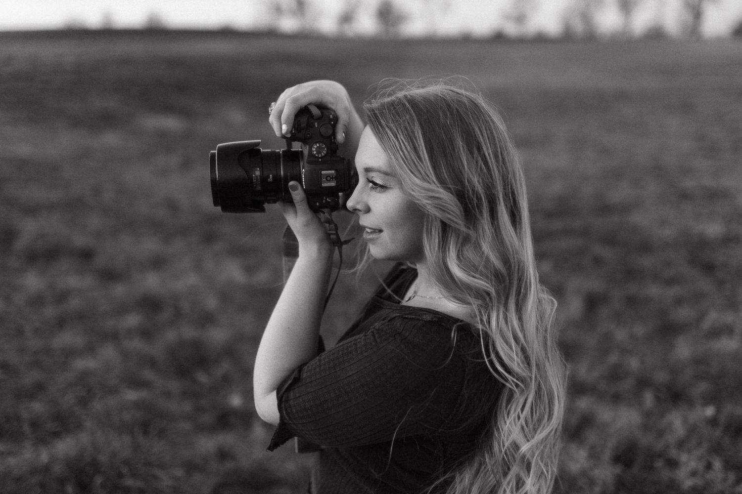 overland park photographer side profile in green field holding a canon camera up to her face to take a photo