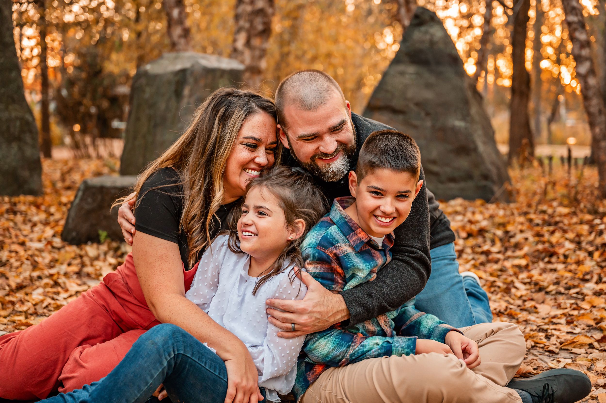 Happy family enjoying autumn day together among fallen leaves.