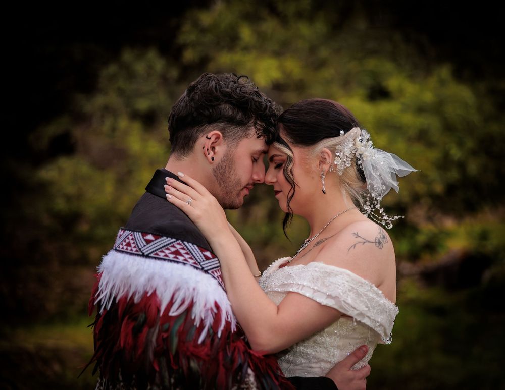 Couple in traditional Maori attire sharing an intimate forehead touch at their wedding ceremony outdoors. Wedding Photography