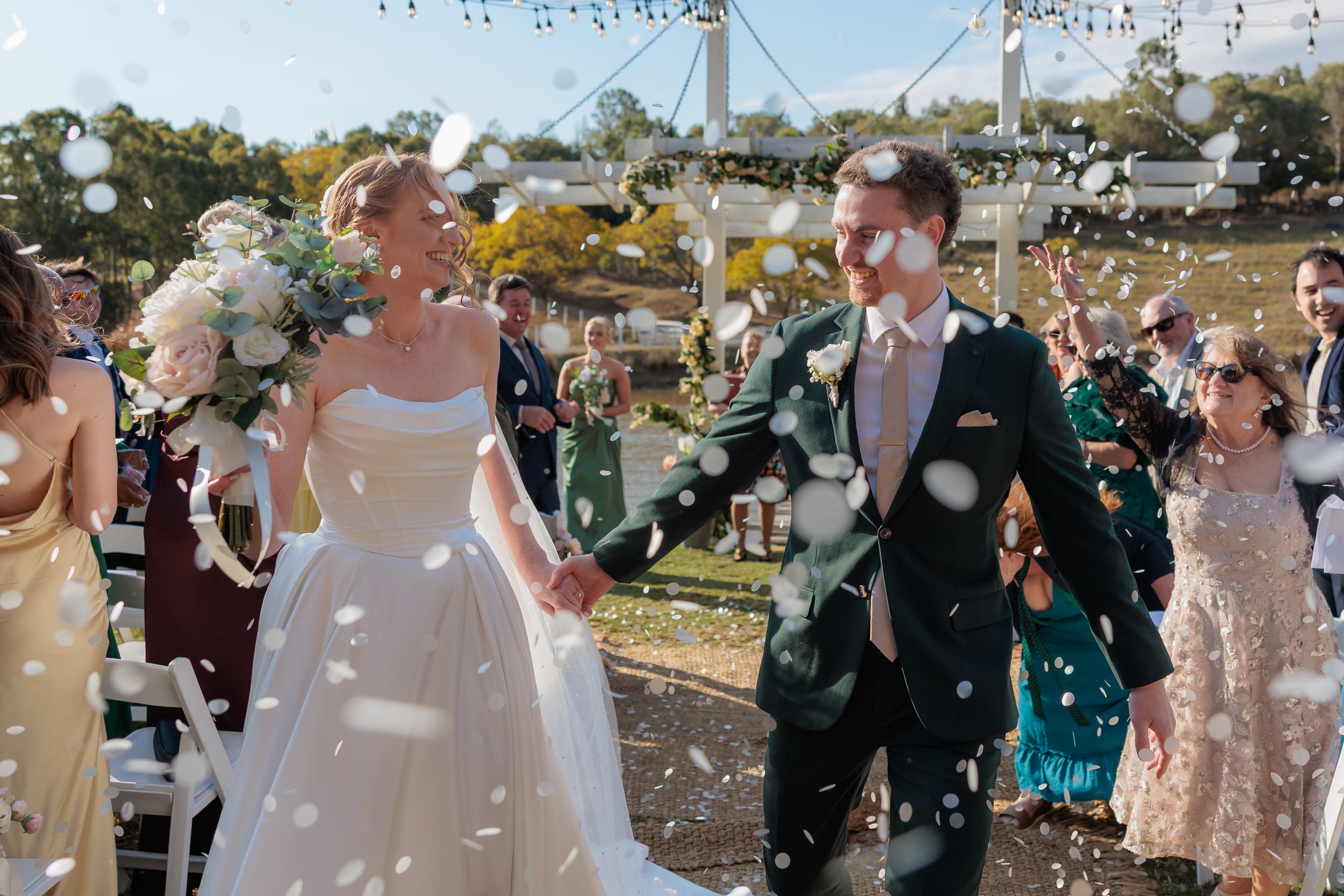 Bride and groom walk through confetti shower at outdoor wedding ceremony. Branell Homestead Laidley Qld, Country wedding photography