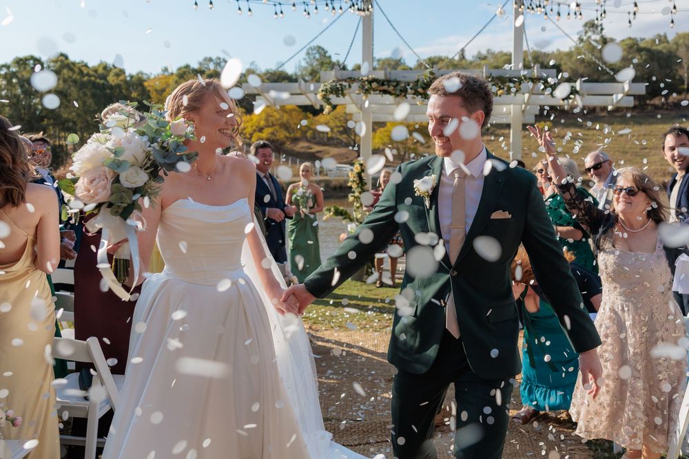 Bride and groom walk through confetti shower at outdoor wedding ceremony. Branell Homestead Laidley Qld, Country wedding photography