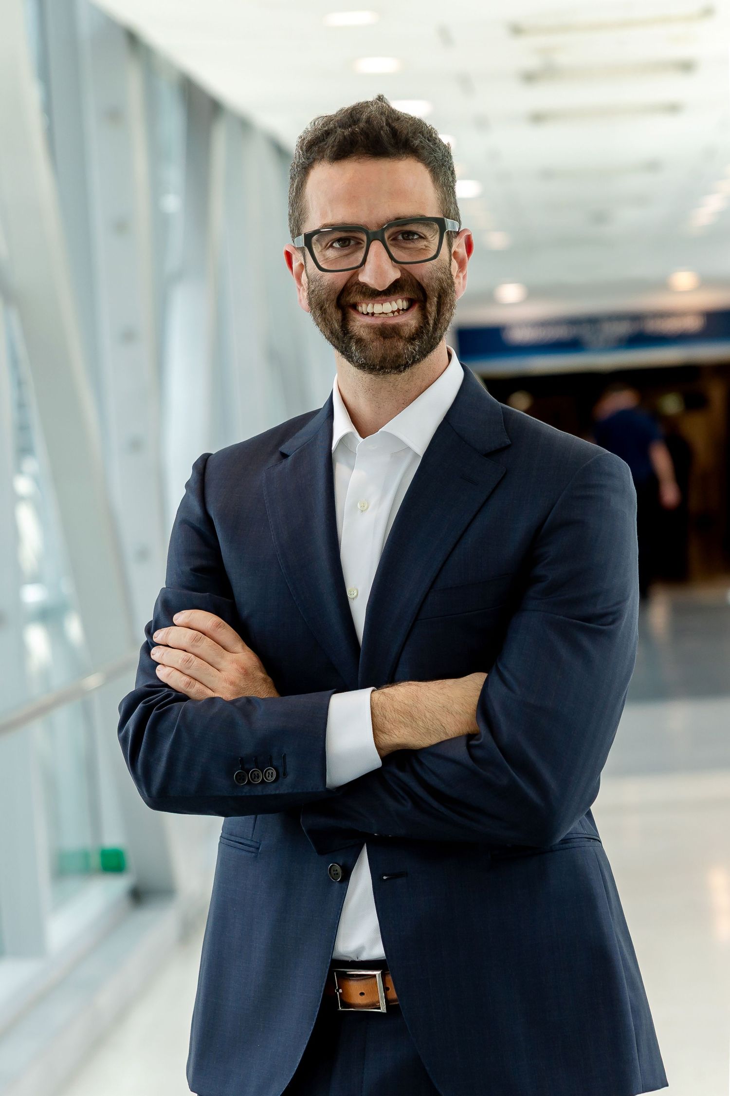 Professional portrait of person in white blazer with city skyline background.