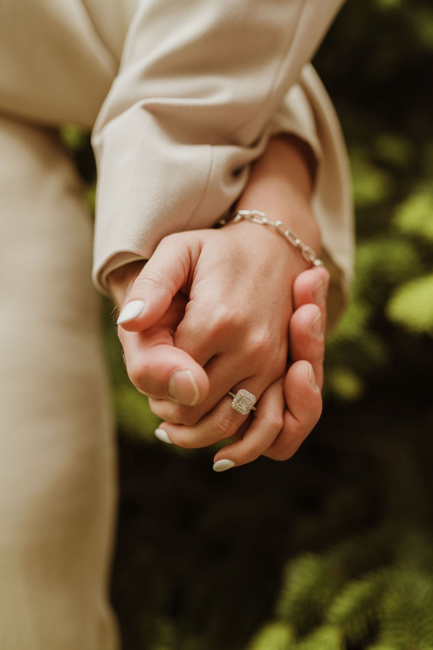 Close-up of intertwined hands showing wedding rings against a blurred background.