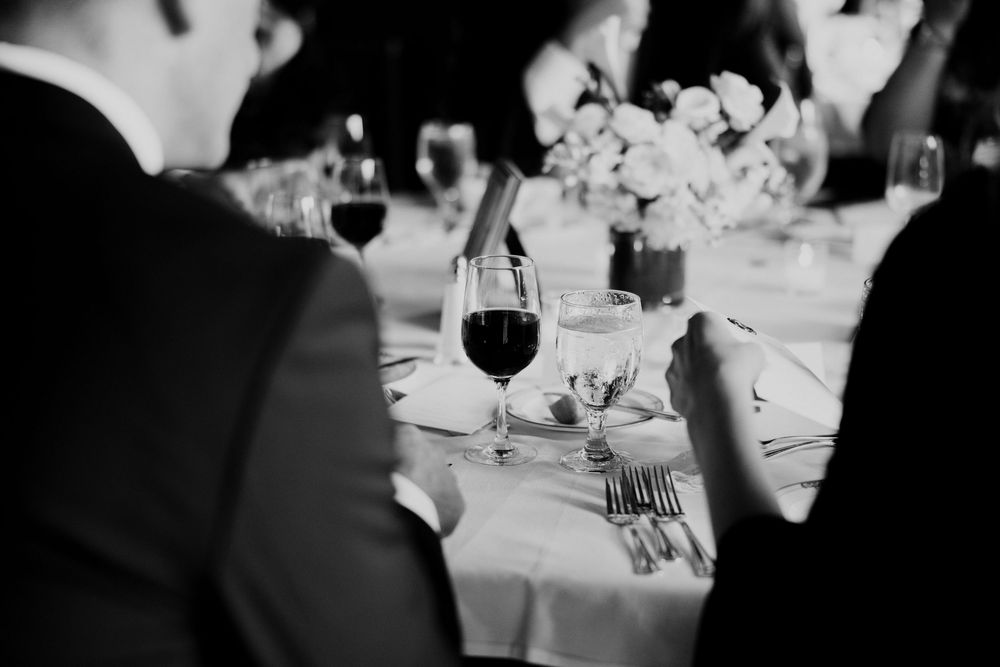 Elegant black and white wedding reception table setting with wine glasses and floral centerpiece.