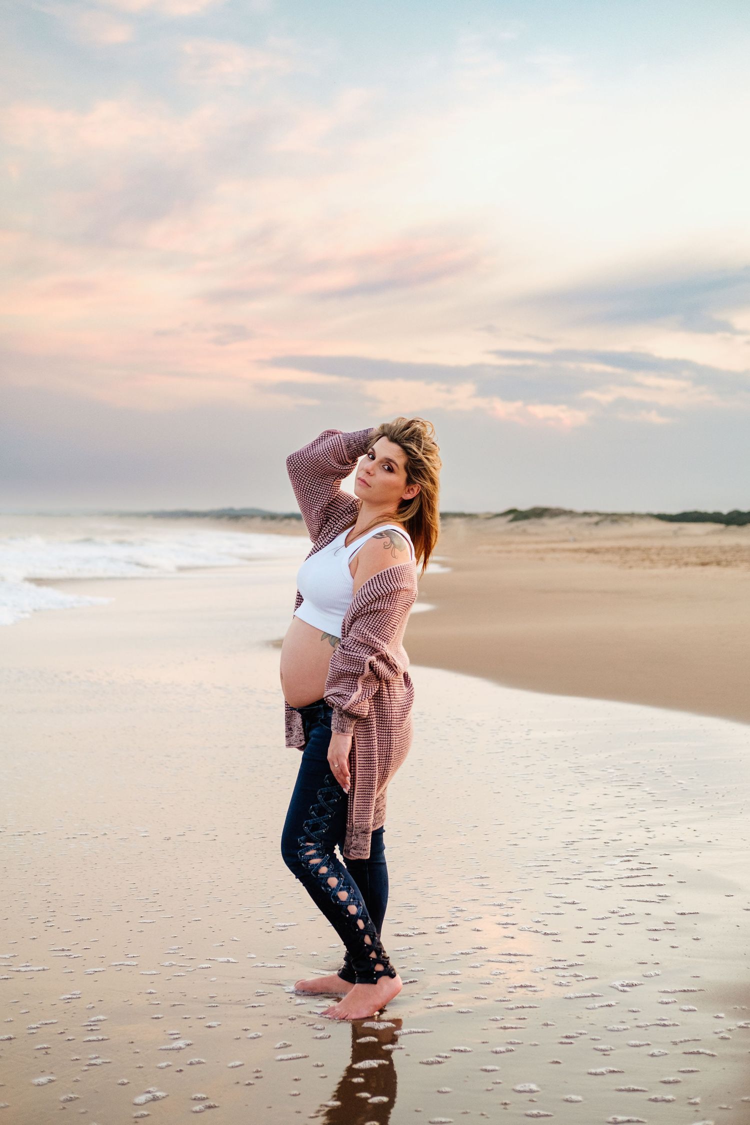 Maternity portrait of a woman standing in shallow water at Mtunzini Beach