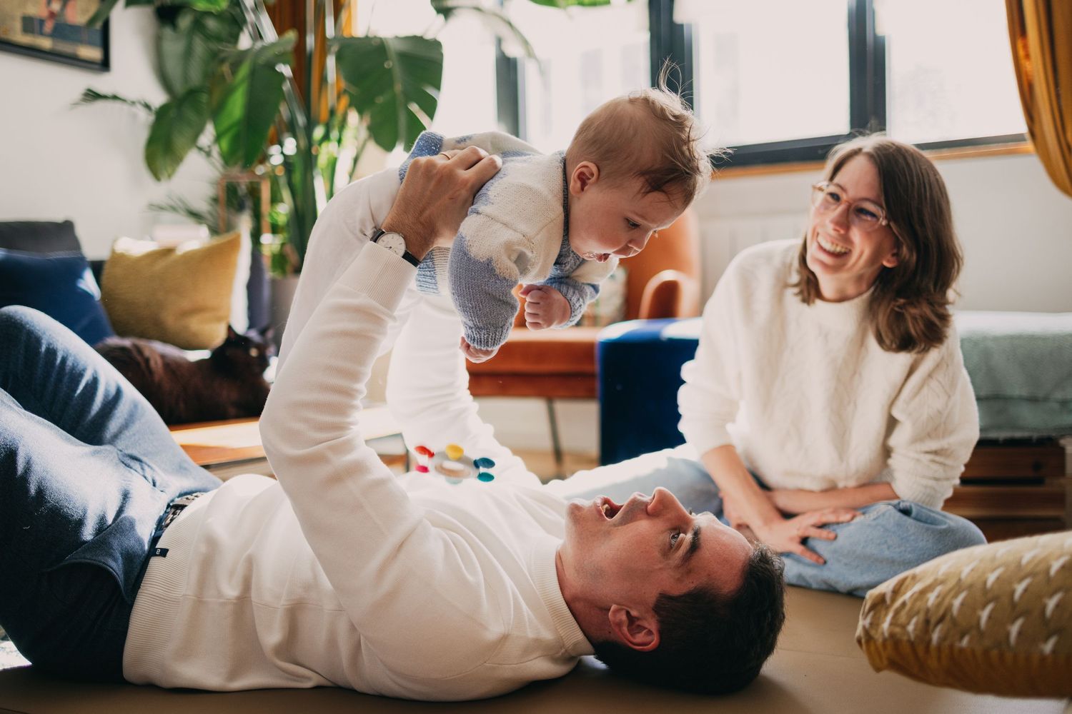 De jeunes parents s'émerveillent avec leur bébé lors d'une séance photo nouveau-né à domicile à Asnières