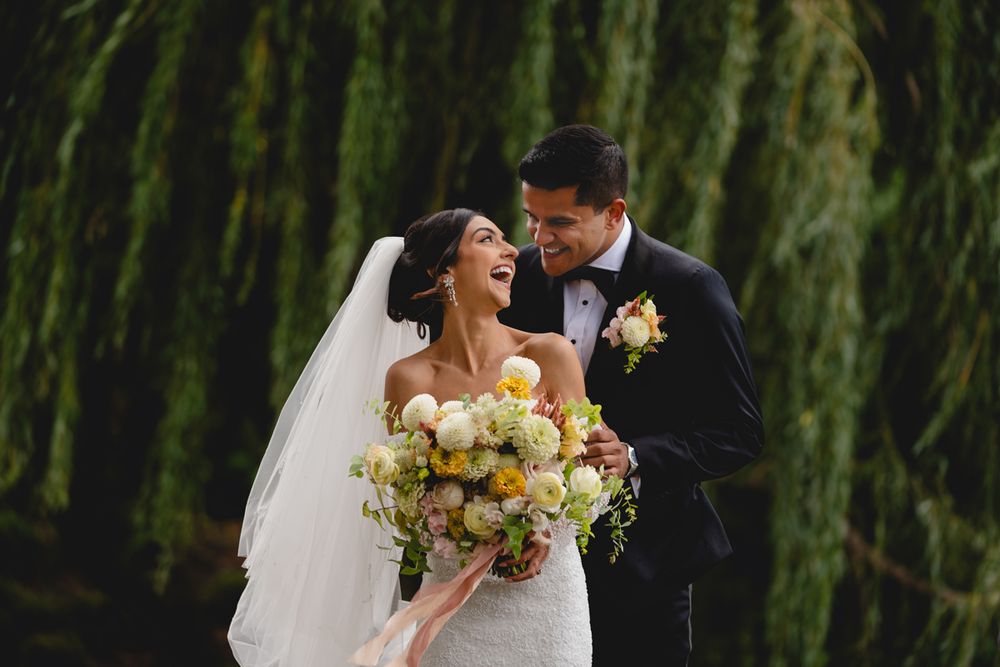 Wedding portrait under weeping willow tree with yellow bouquet.